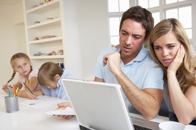 Young couple using laptop computer in kitchen looking concerned